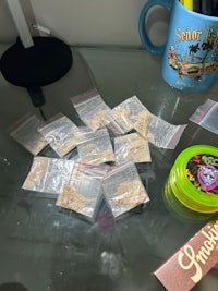 a desk with several bags of marijuana and a cup of coffee