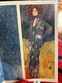 a woman is holding up a painting by gustav klimt