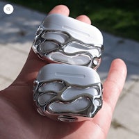 two silver airpods in a person's hand